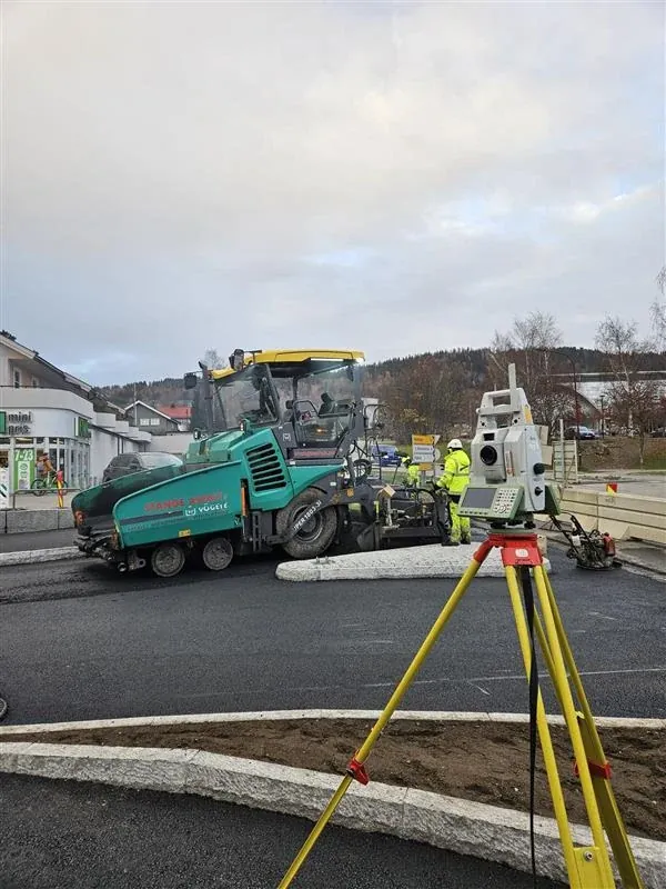 Totalstasjon ved asfaltarbeid med asfaltutlegger og mannskap i bakgrunnen