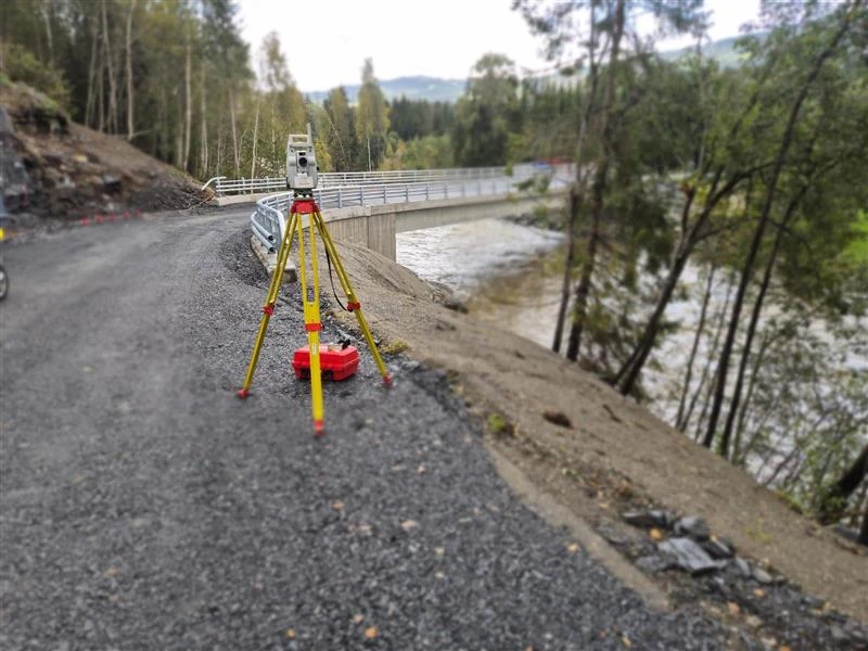 Totalstasjon satt opp ved en bru over elv